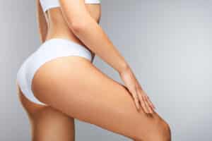 Close-up of a woman's upper thigh and hip in white underwear, showing smooth skin and toned contours