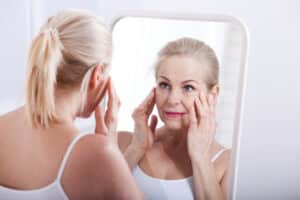 Woman looking in the mirror at swelling after a facelift in Grand Rapids, MI