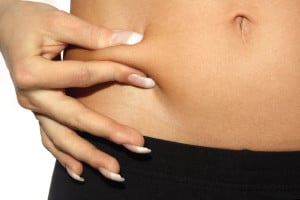 Close up of woman pinching her belly fat with white background