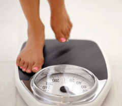 close up pf woman stepping on scale