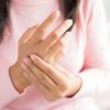 Closeup woman sitting on sofa holds her wrist hand injury, feeling pain. Health care and medical concept.