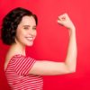 Photo of rejoicing wavy curly woman after having done two pushups while isolated with red background