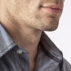 Close-up of man's chin and jawline with facial hair beard stubble five o'clock shadow. Men's personal care and grooming.