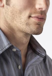 Close-up of man's chin and jawline with facial hair beard stubble five o'clock shadow. Men's personal care and grooming.