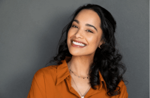 young woman with beautiful smile on grey wall