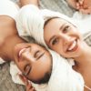 Two,Young,Beautiful,Smiling,Women,In,White,Bathrobes,And,Towels