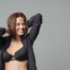 Smiling woman in bra posing over gray background