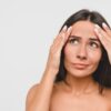 Woman looking at forehead wrinkles, considering a forehead lift.
