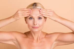 Beautiful mature woman touching smoothed out forehead after brow lift