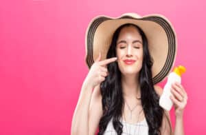 Woman large sunhat applying spf sunscreen to prevent skin cancer