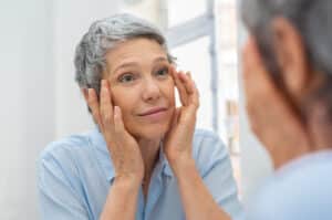 Older woman looking at eyelids and forehead in mirror